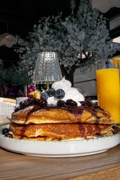 A stack of pancakes with blueberry compote, fresh blueberries, and whipped cream at Bloom Room