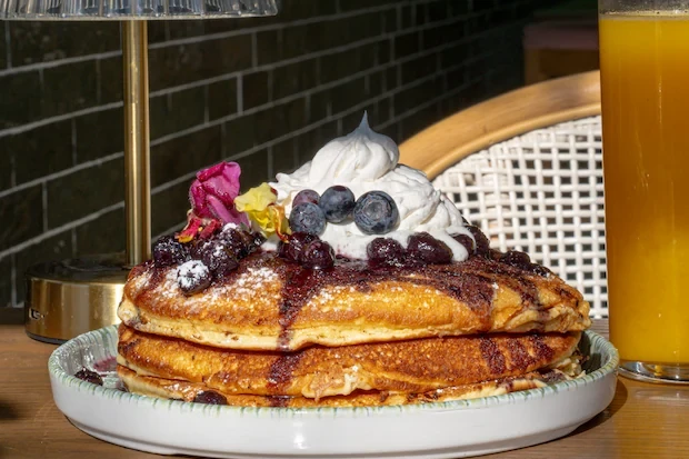Blueberry pancakes with whipped cream and a fresh orange juice