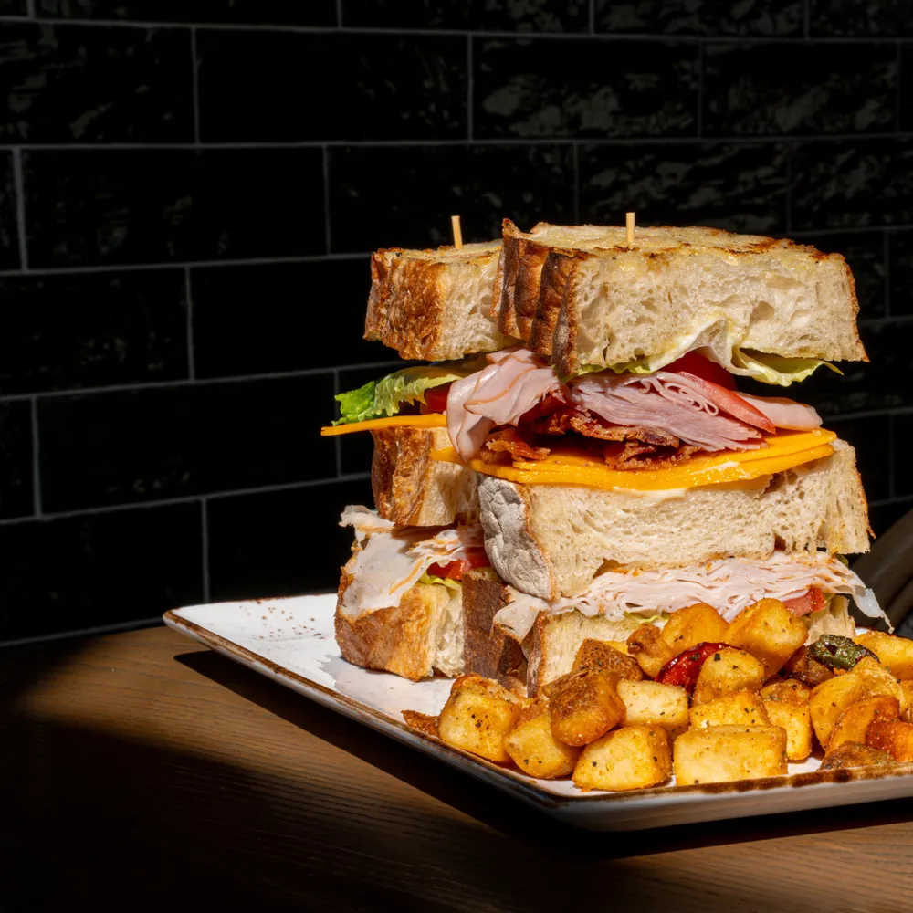 Massive club sandwich with breakfast potatoes
